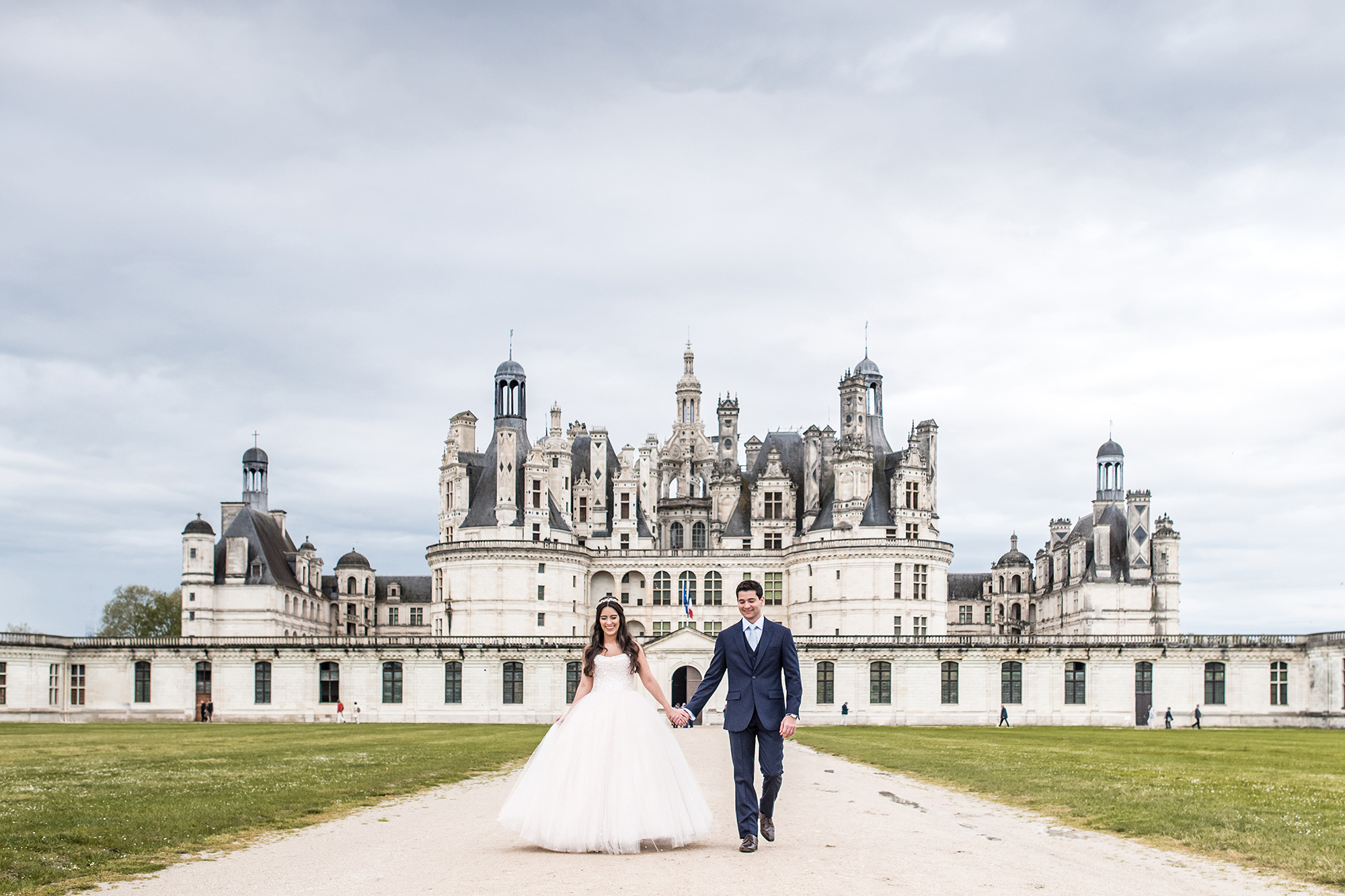 les mariés se tiennet devant le féérique château de chambord, château de la loire classé au patrimoine mondial de l'humanité